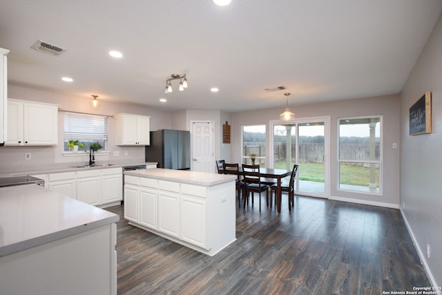 kitchen featuring decorative light fixtures, stainless steel appliances, white cabinets, and a kitchen island