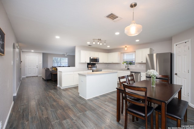 kitchen featuring appliances with stainless steel finishes, decorative light fixtures, sink, white cabinets, and kitchen peninsula