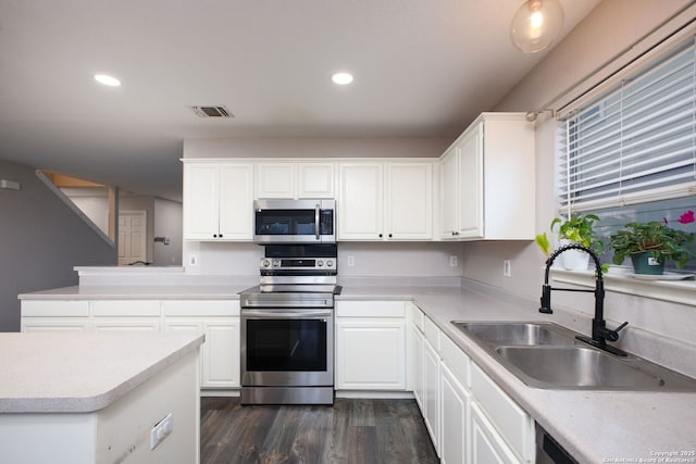 kitchen featuring sink, white cabinetry, appliances with stainless steel finishes, dark hardwood / wood-style flooring, and kitchen peninsula