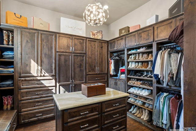 spacious closet featuring dark hardwood / wood-style floors and a chandelier