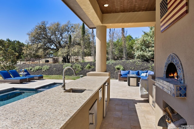 view of patio featuring sink, a fenced in pool, and an outdoor living space with a fireplace