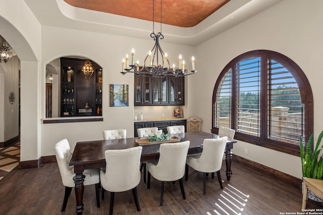 dining area with a tray ceiling, dark wood-type flooring, and a chandelier