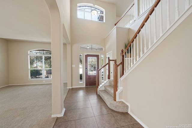 carpeted foyer entrance featuring a towering ceiling and a healthy amount of sunlight