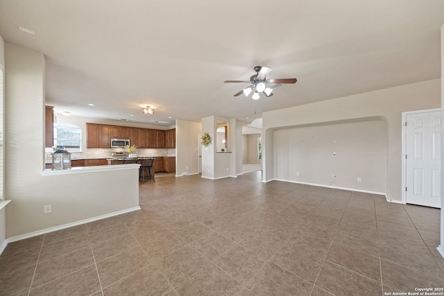 unfurnished living room featuring tile patterned floors and ceiling fan