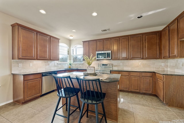 kitchen featuring appliances with stainless steel finishes, a center island, sink, and backsplash