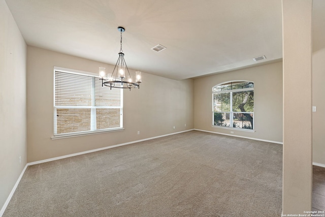 spare room with carpet flooring and a chandelier