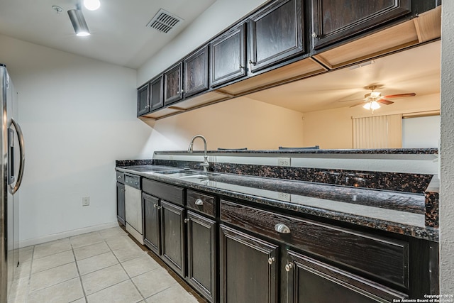 kitchen with light tile patterned flooring, dark brown cabinetry, sink, appliances with stainless steel finishes, and dark stone counters