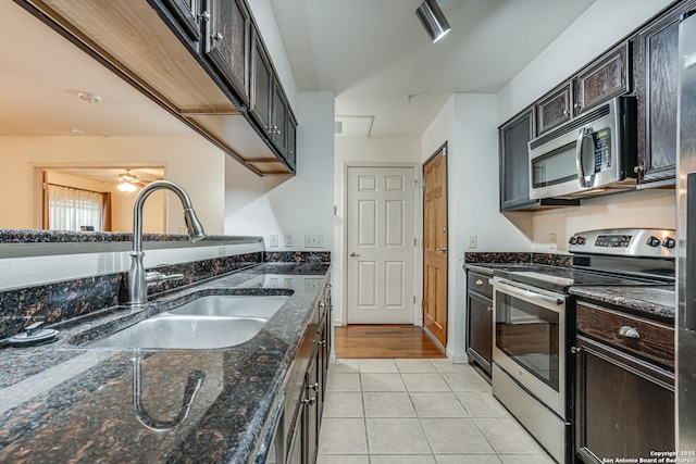 kitchen with sink, dark stone counters, light tile patterned floors, stainless steel appliances, and dark brown cabinets