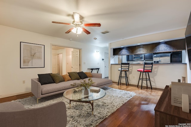 living room with dark wood-type flooring and ceiling fan