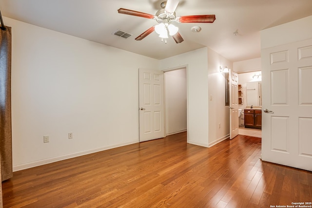 unfurnished bedroom featuring hardwood / wood-style floors, ceiling fan, and ensuite bathroom