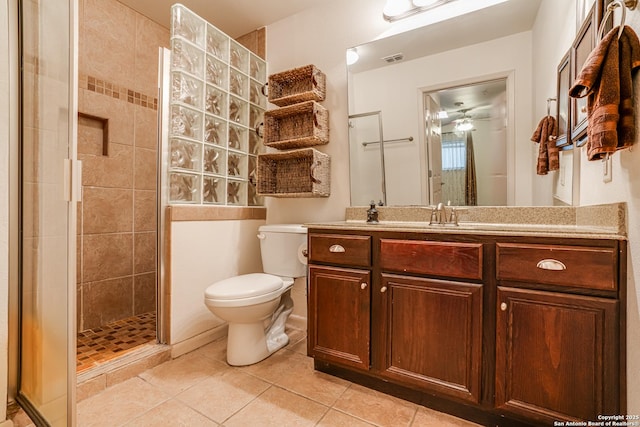 bathroom featuring tiled shower, vanity, toilet, and tile patterned flooring