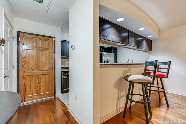 bar with sink, stainless steel fridge, and wood-type flooring