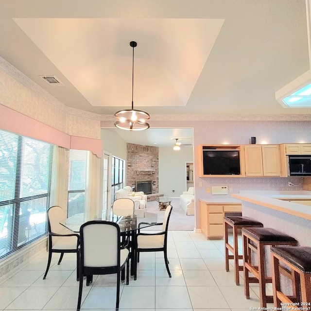 tiled dining room featuring a tray ceiling and a large fireplace