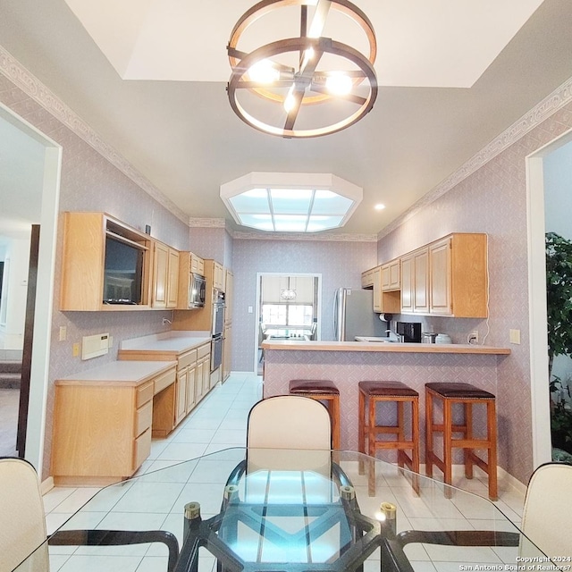 kitchen with a breakfast bar, light brown cabinetry, light tile patterned floors, kitchen peninsula, and stainless steel appliances