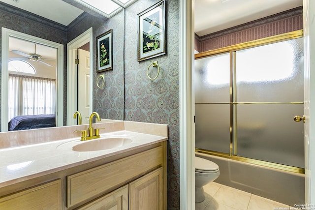 full bathroom featuring ceiling fan, tile patterned flooring, bath / shower combo with glass door, vanity, and toilet