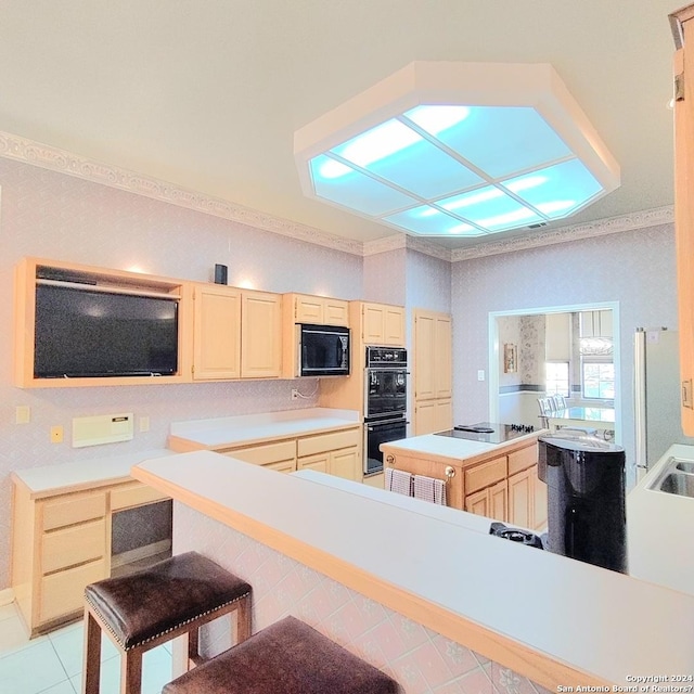 kitchen featuring a kitchen bar, kitchen peninsula, light brown cabinets, and black appliances