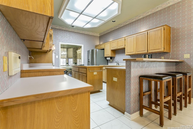 kitchen featuring light tile patterned flooring, a kitchen island, a breakfast bar area, kitchen peninsula, and stainless steel refrigerator with ice dispenser