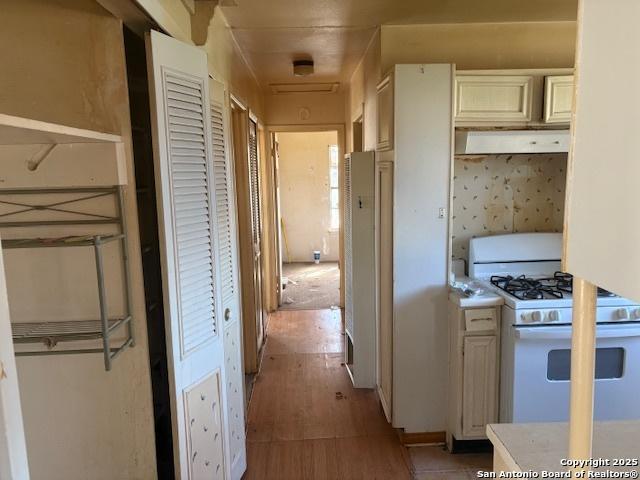 kitchen featuring cream cabinets, white gas range oven, and light wood-type flooring