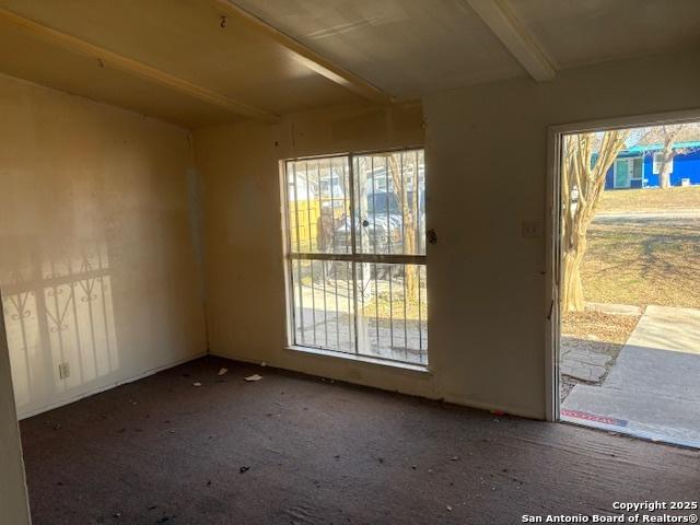 carpeted spare room featuring beamed ceiling