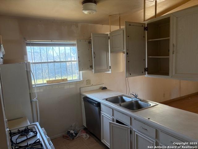 kitchen with stainless steel dishwasher, sink, white fridge, and stove