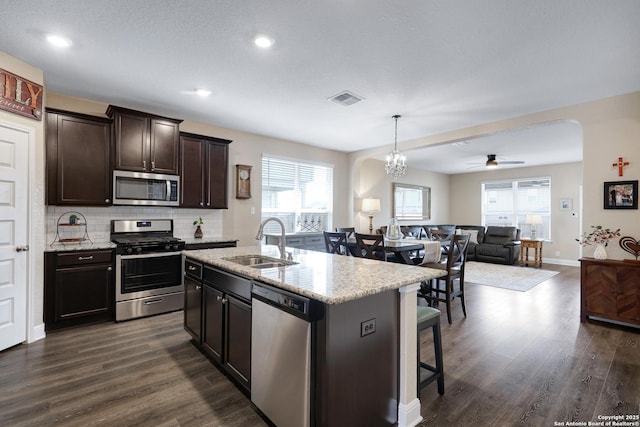 kitchen with sink, dark hardwood / wood-style flooring, an island with sink, pendant lighting, and stainless steel appliances