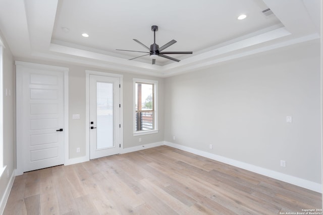 spare room featuring ceiling fan, a raised ceiling, and light hardwood / wood-style floors