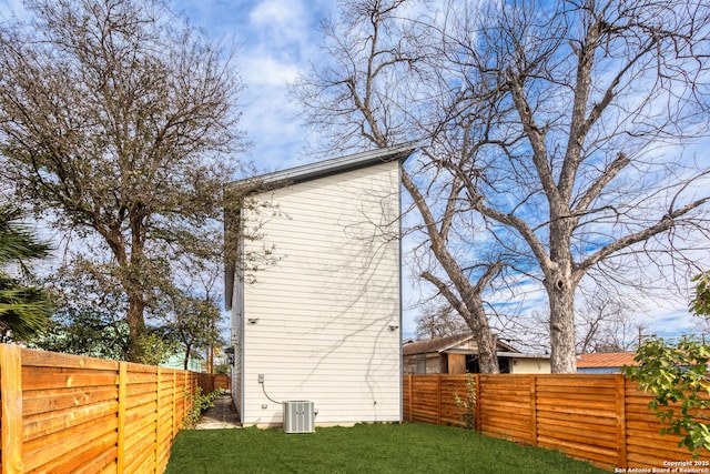 view of side of property featuring cooling unit and a lawn