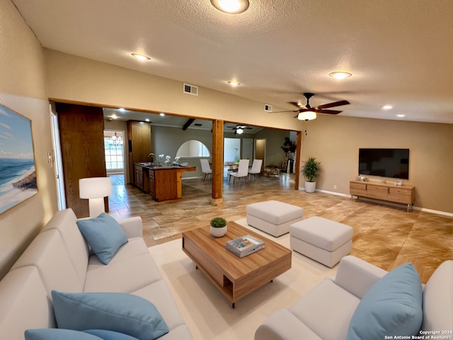 living room featuring sink, a textured ceiling, and ceiling fan