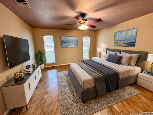 bedroom featuring multiple windows, ceiling fan, and a textured ceiling