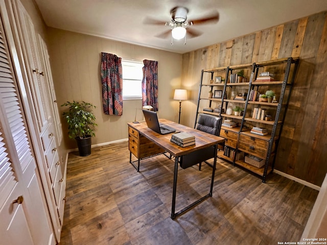 office space with dark hardwood / wood-style floors, ceiling fan, and wood walls