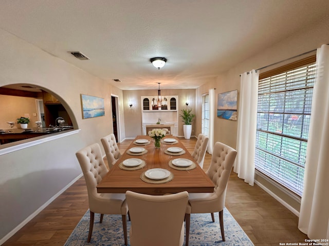 dining room with an inviting chandelier, dark hardwood / wood-style floors, and a textured ceiling