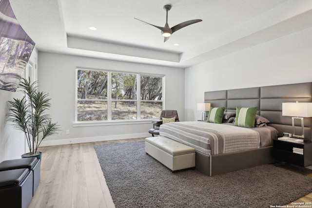 bedroom featuring hardwood / wood-style flooring, a raised ceiling, and ceiling fan