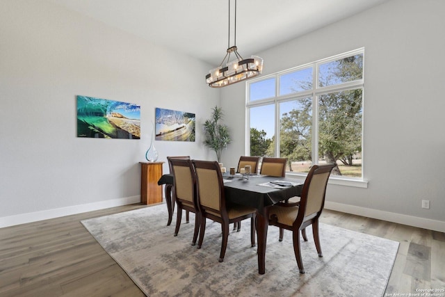 dining space with hardwood / wood-style floors and a notable chandelier