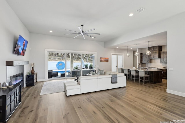 living room with a tiled fireplace and light hardwood / wood-style flooring