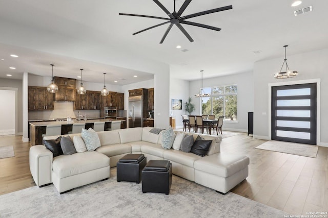 living room featuring sink, a chandelier, and light wood-type flooring