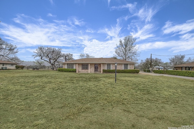 view of front of home with brick siding, driveway, and a front lawn