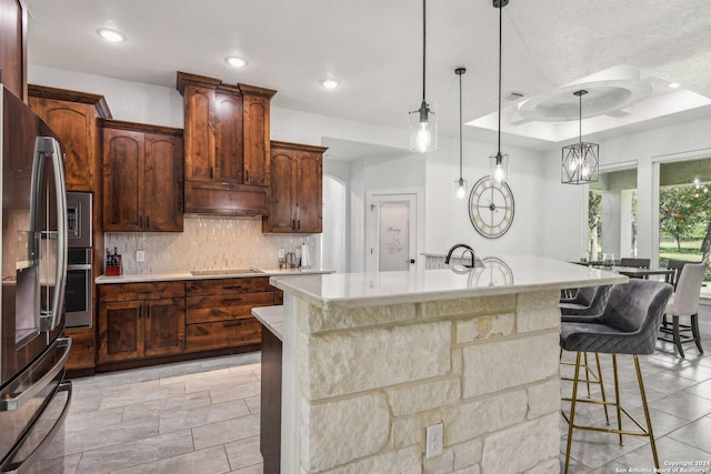 kitchen with tasteful backsplash, light countertops, appliances with stainless steel finishes, and a kitchen bar