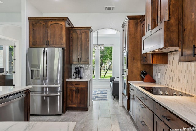 kitchen with appliances with stainless steel finishes, arched walkways, visible vents, and tasteful backsplash