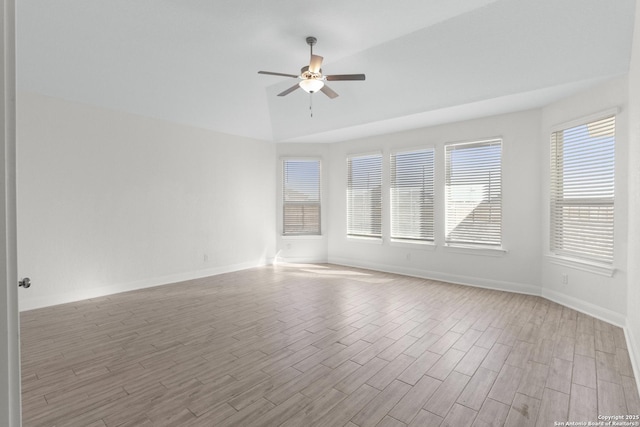 spare room featuring ceiling fan, vaulted ceiling, and light wood-type flooring