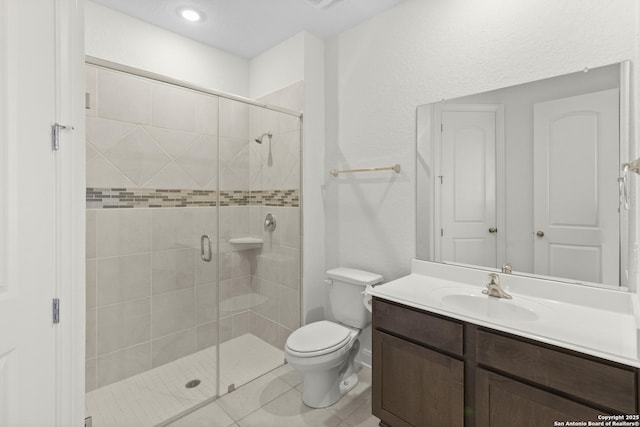 bathroom with vanity, tile patterned floors, a shower with door, and toilet