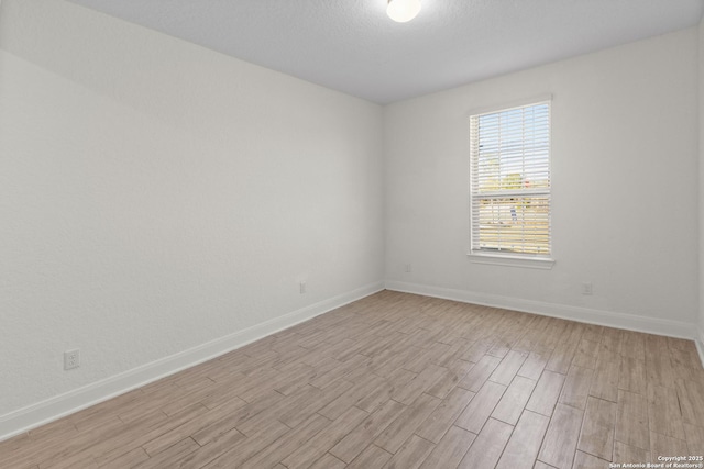 unfurnished room with light hardwood / wood-style flooring and a textured ceiling