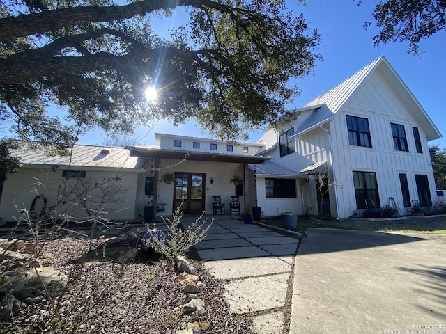 rear view of house with metal roof, french doors, and board and batten siding