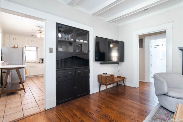 living room featuring ceiling fan, dark hardwood / wood-style floors, sink, and beam ceiling