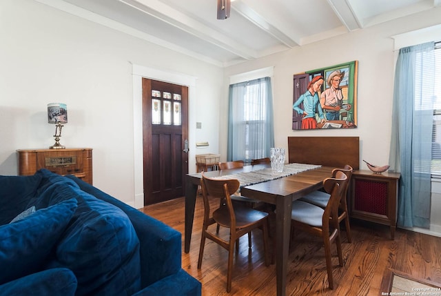 dining room featuring dark wood-type flooring, plenty of natural light, and beamed ceiling