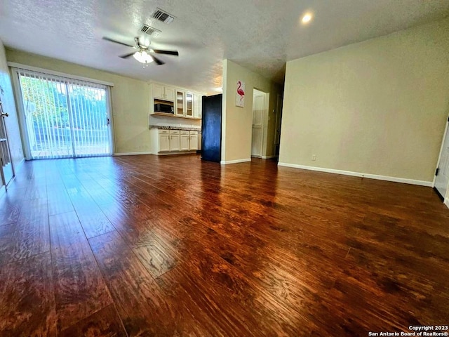 unfurnished living room with ceiling fan, dark hardwood / wood-style floors, and a textured ceiling