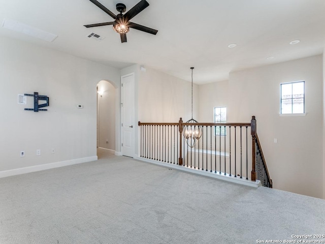 spare room with ceiling fan with notable chandelier and light colored carpet