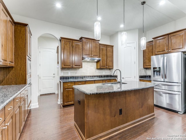 kitchen featuring pendant lighting, sink, a kitchen island with sink, dark stone countertops, and stainless steel appliances