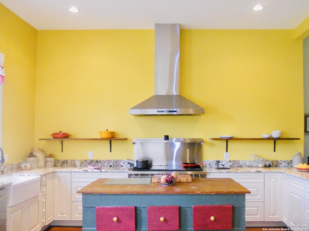 kitchen featuring sink, white cabinets, light stone counters, and wall chimney exhaust hood