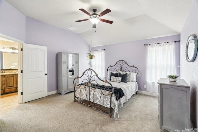 bedroom featuring multiple windows, ensuite bath, vaulted ceiling, and light colored carpet