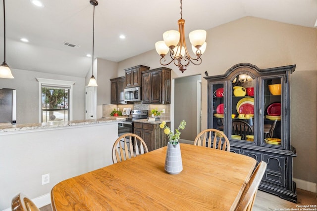 dining area featuring light hardwood / wood-style flooring, a notable chandelier, and vaulted ceiling